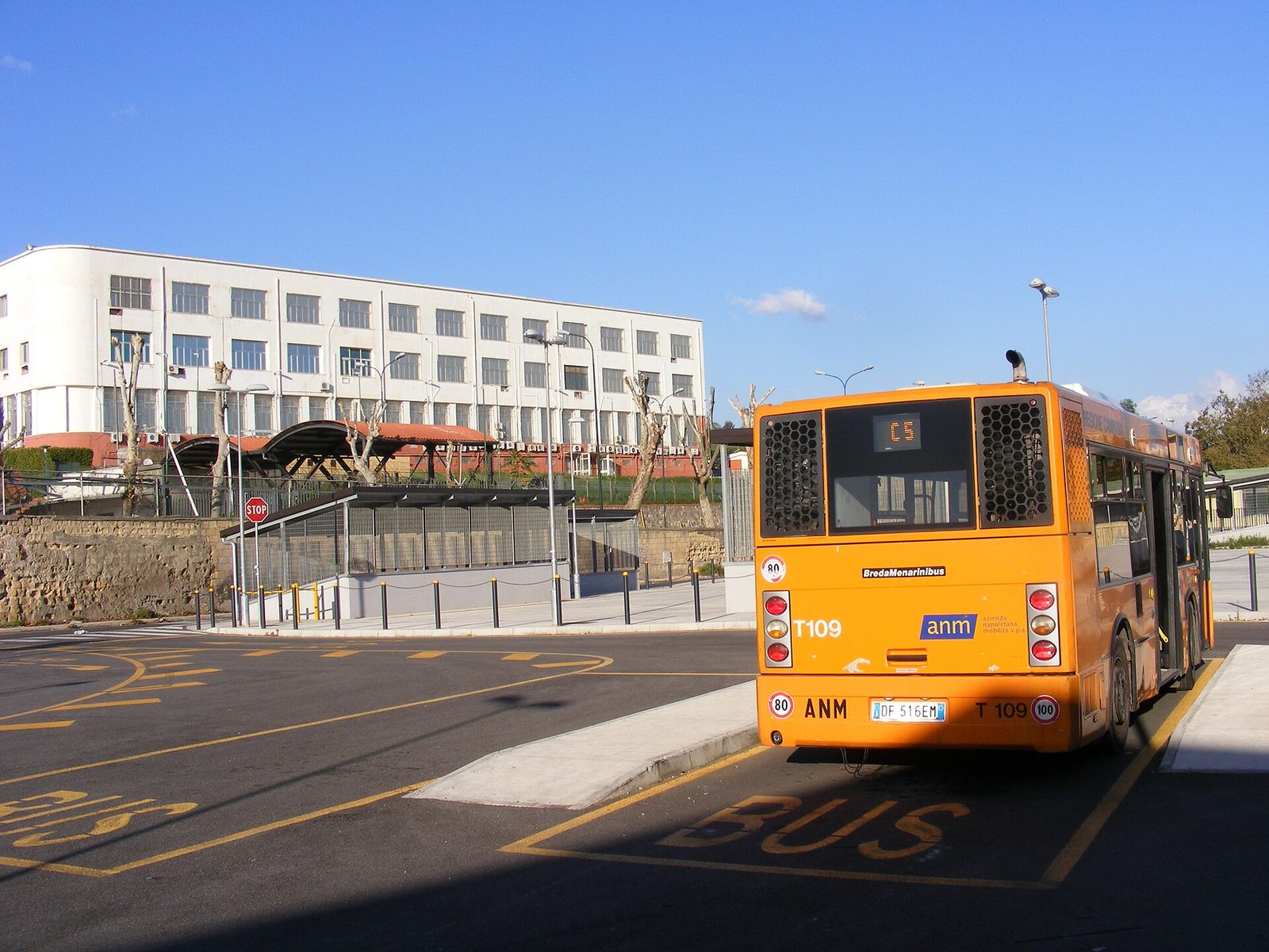 An orange ANM city bus at the Bagnoli station stop in Naples