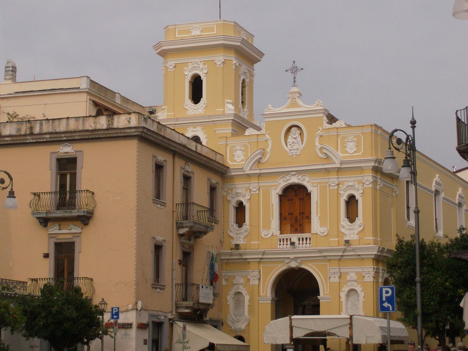 A yellow baroque church facade with a bell tower in the center of Sorrento
