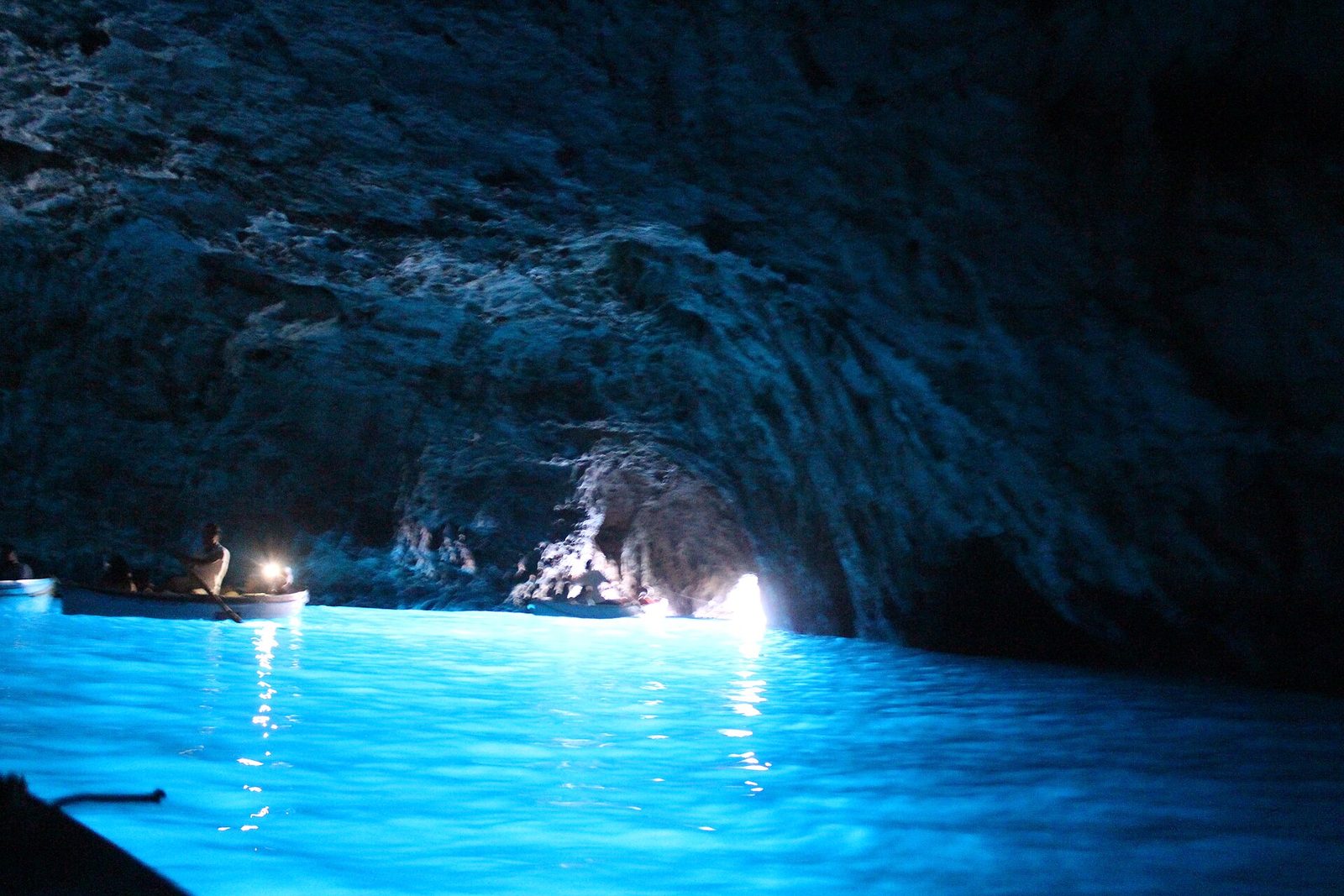 Rowboats inside the Blue Grotto on Capri, with the water lit an intense blue
