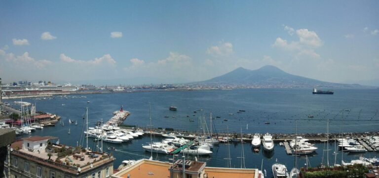 Fishing boats in the Borgo Marinari harbor with Mount Vesuvius across the bay, a classic view among things to do in Naples, Italy