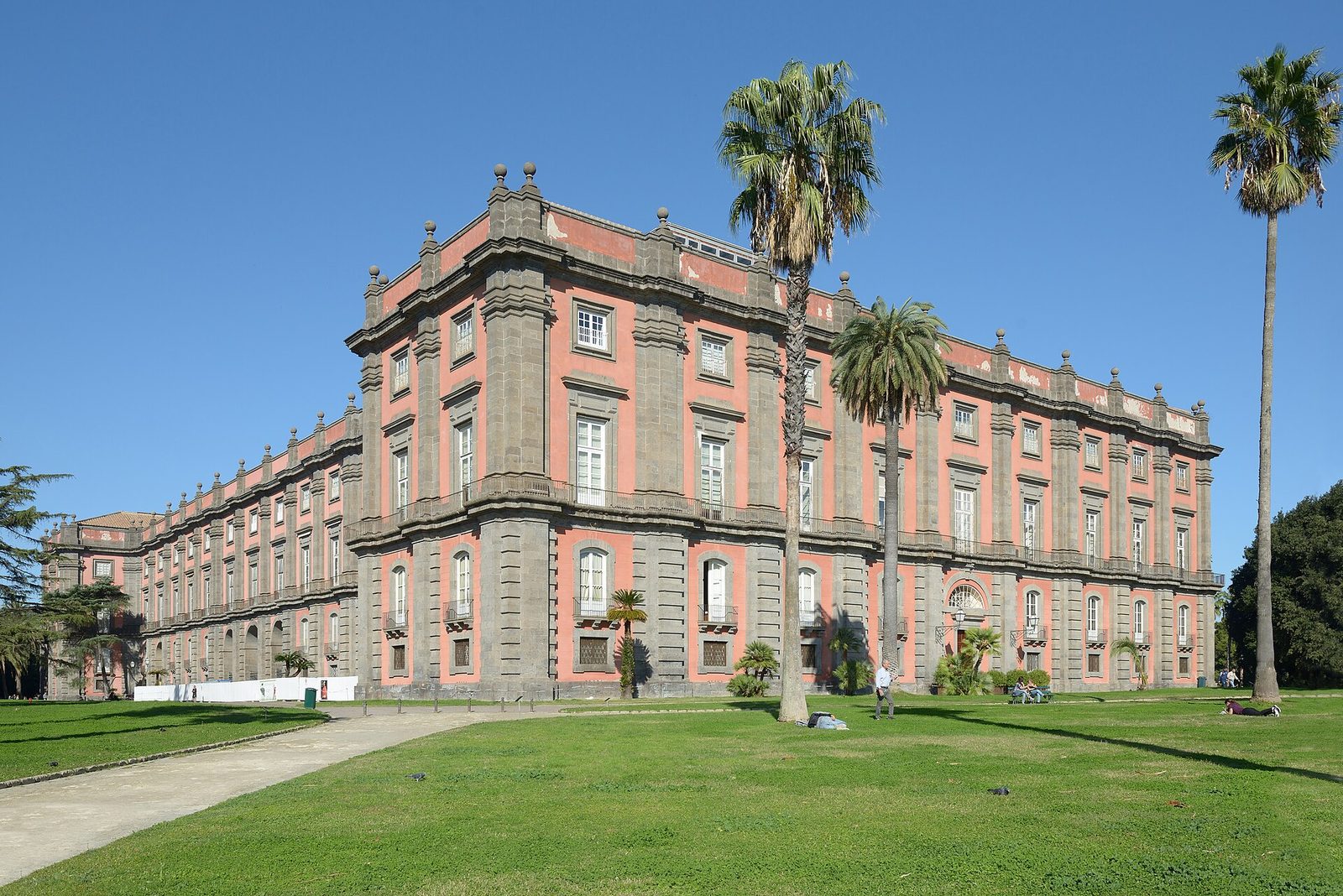 The red and gray facade of the Royal Palace of Capodimonte, home of one of the great Naples museums, set in its park