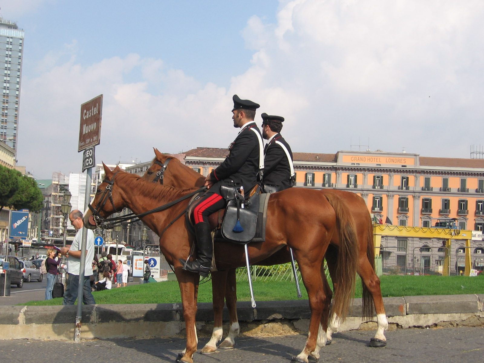 Two mounted Carabinieri officers on patrol beside a city street in Italy
