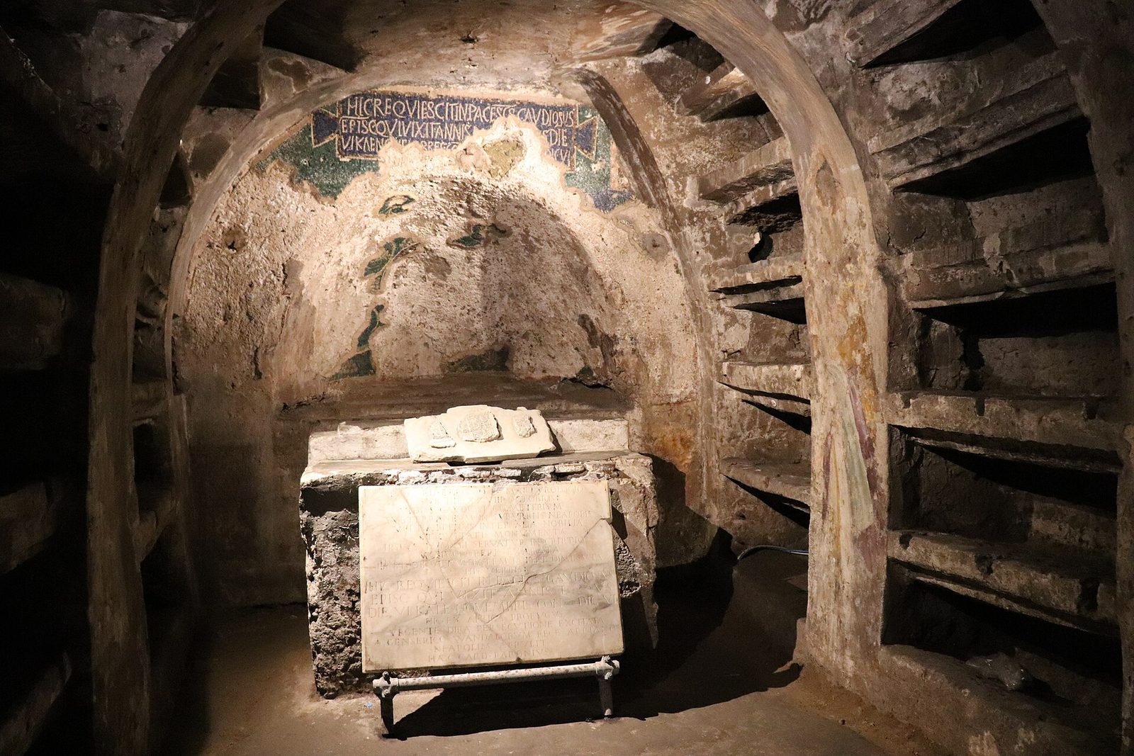 A lit burial chamber with wall niches and a stone tomb in the Catacombs of San Gaudioso under Santa Maria della Sanità