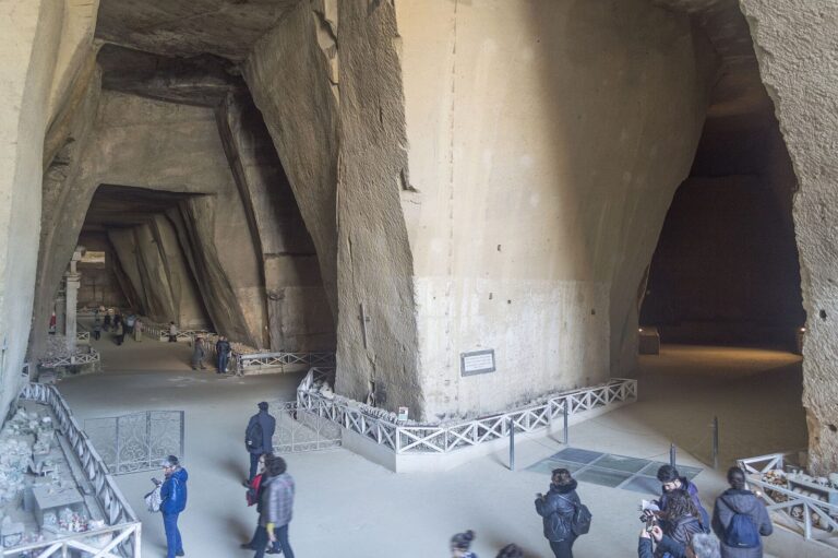 Visitors walking through the vast tuff quarry caverns of the Cimitero delle Fontanelle ossuary in Naples
