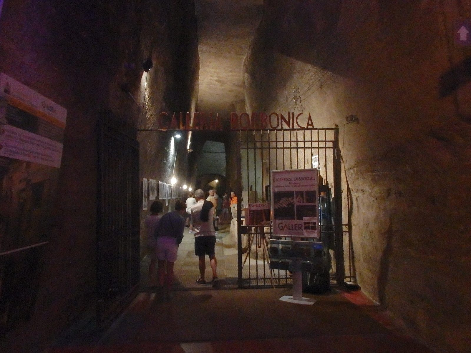 The gated underground entrance hall of the Galleria Borbonica tunnel in Naples, with visitors starting a tour