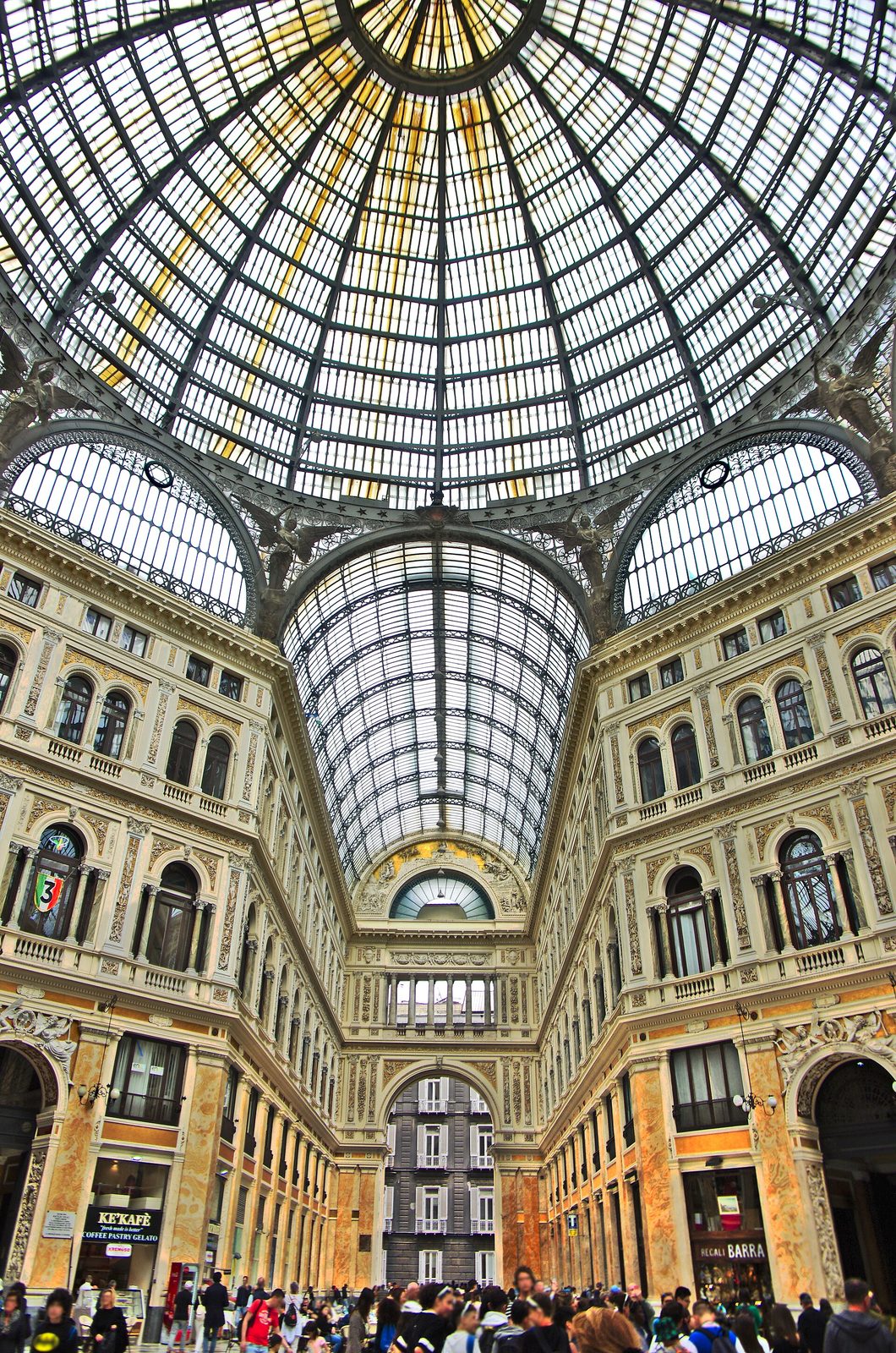 The glass and iron dome of the Galleria Umberto I arcade in Naples, with people below