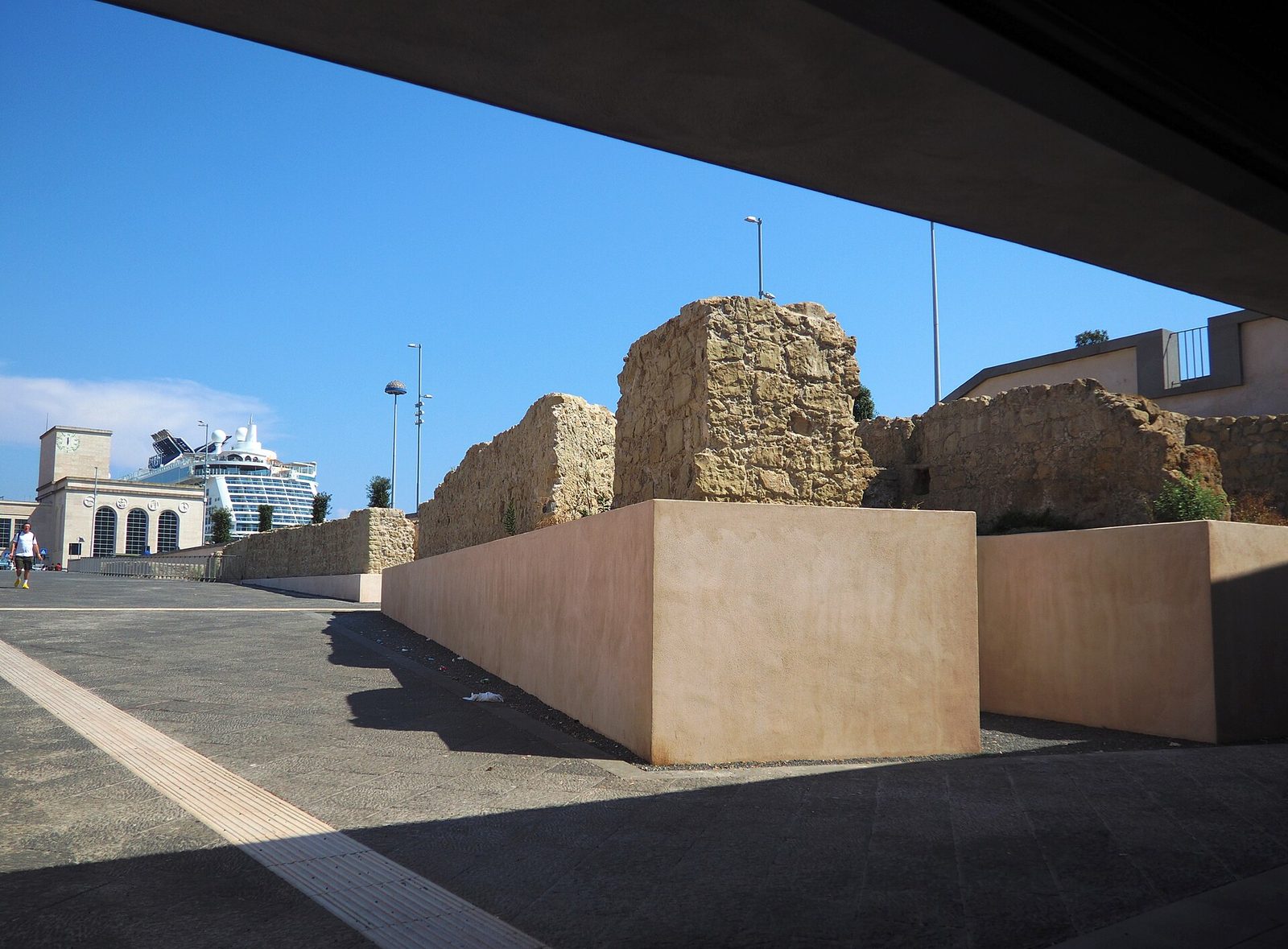 Getting around Naples Italy by metro: the Municipio station exit beside the port, with ancient wall remains and a cruise ship behind