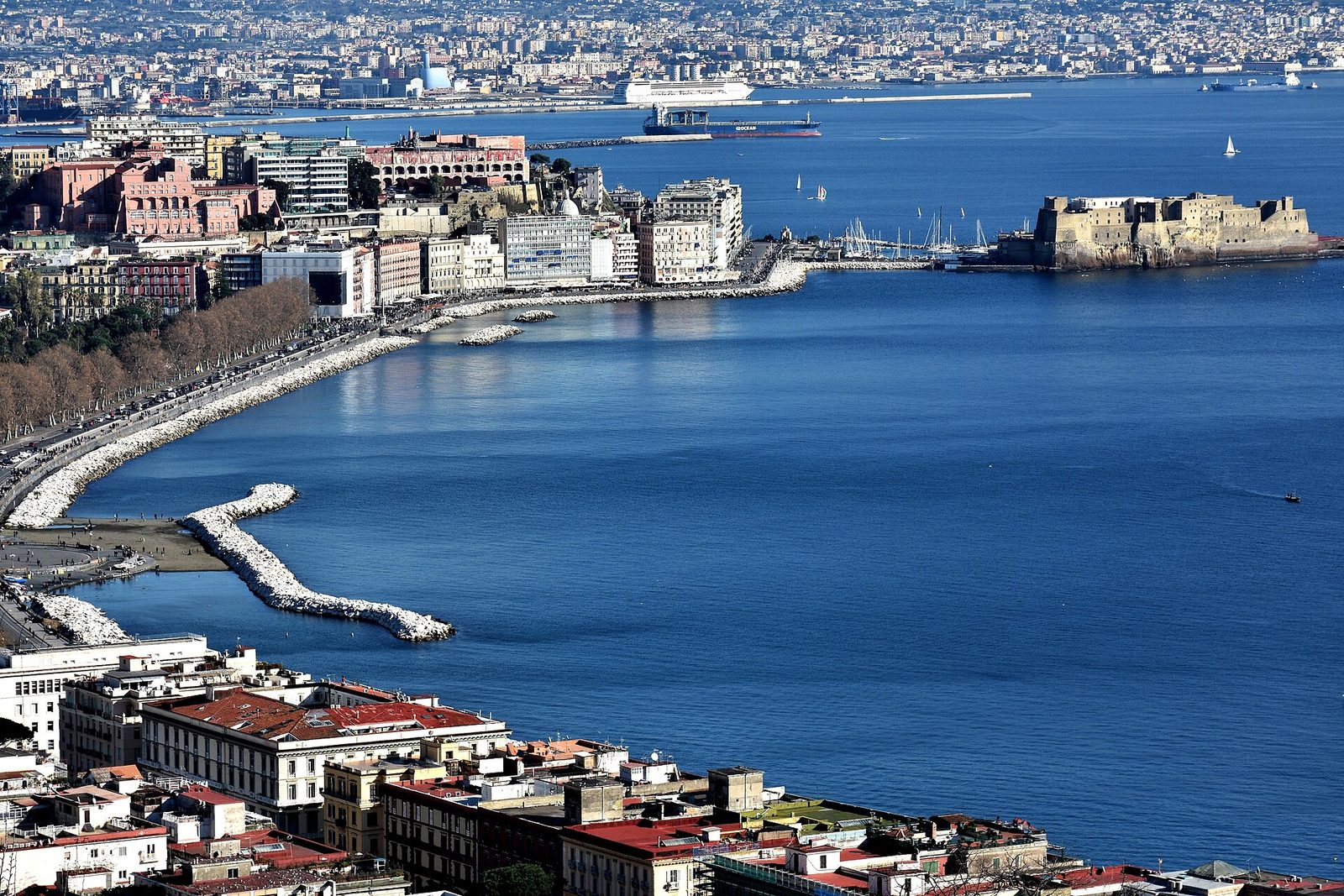 The Naples seafront curving toward Castel dell'Ovo, with the bay and the city spread out behind