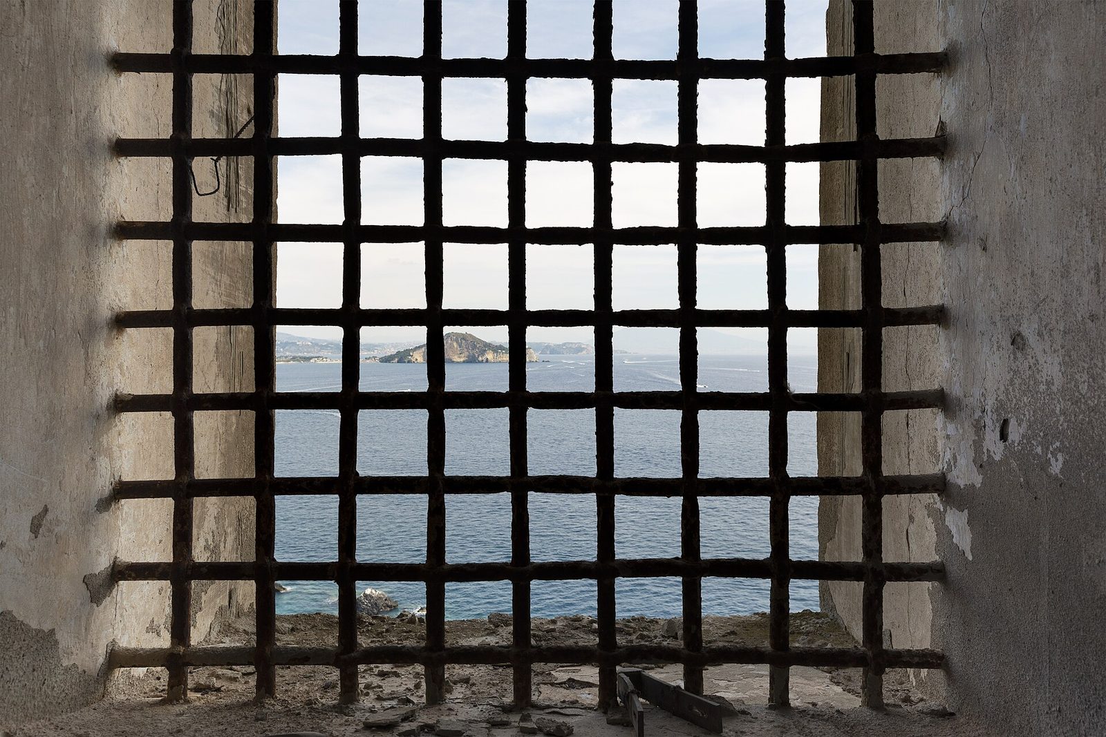 The barred window of a former prison cell in Palazzo d'Avalos on Procida, looking out over the sea