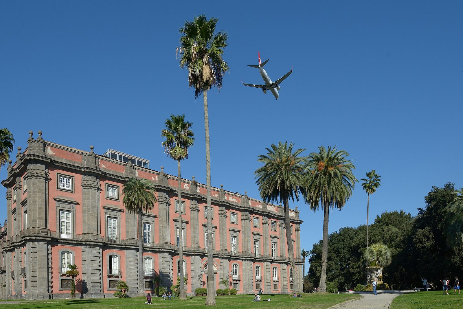 A passenger jet flying low over the Capodimonte palace, showing how close Naples airport is to the city