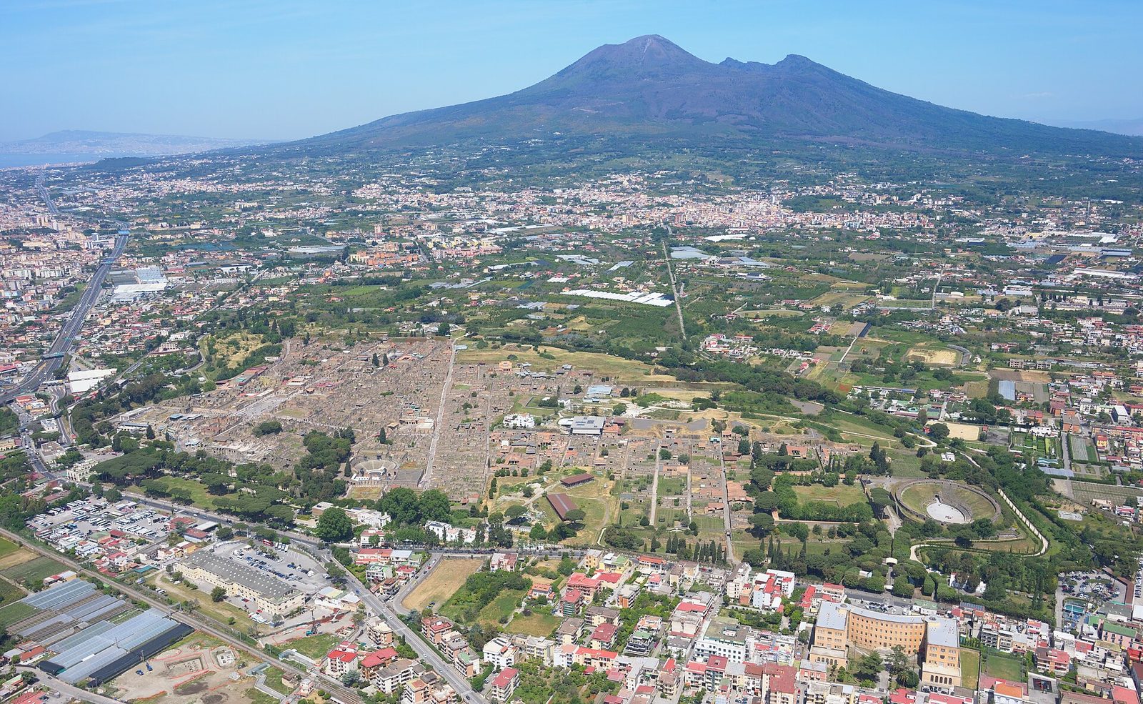 Aerial view of the ruins of Pompeii with Mount Vesuvius rising behind the modern town