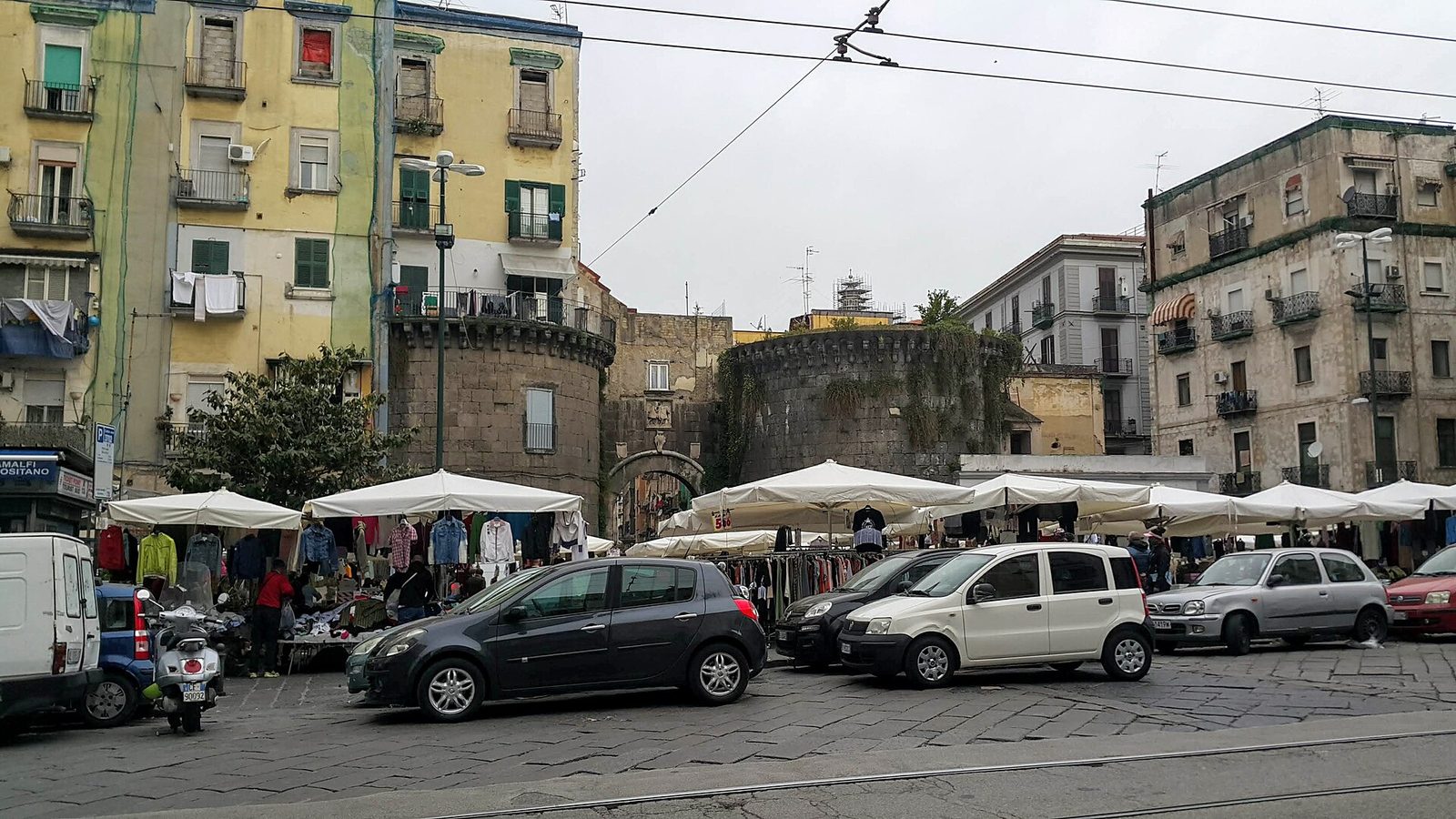 Market stalls under umbrellas in the street by Porta Nolana in Naples, one of the city's cheapest places to shop for food