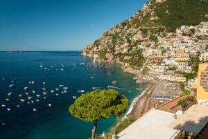 Positano's pastel houses climbing the hillside above the beach and boats on the Amalfi Coast