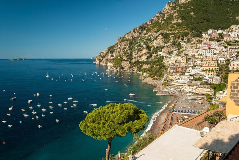 Positano's pastel houses climbing the hillside above the beach and boats on the Amalfi Coast