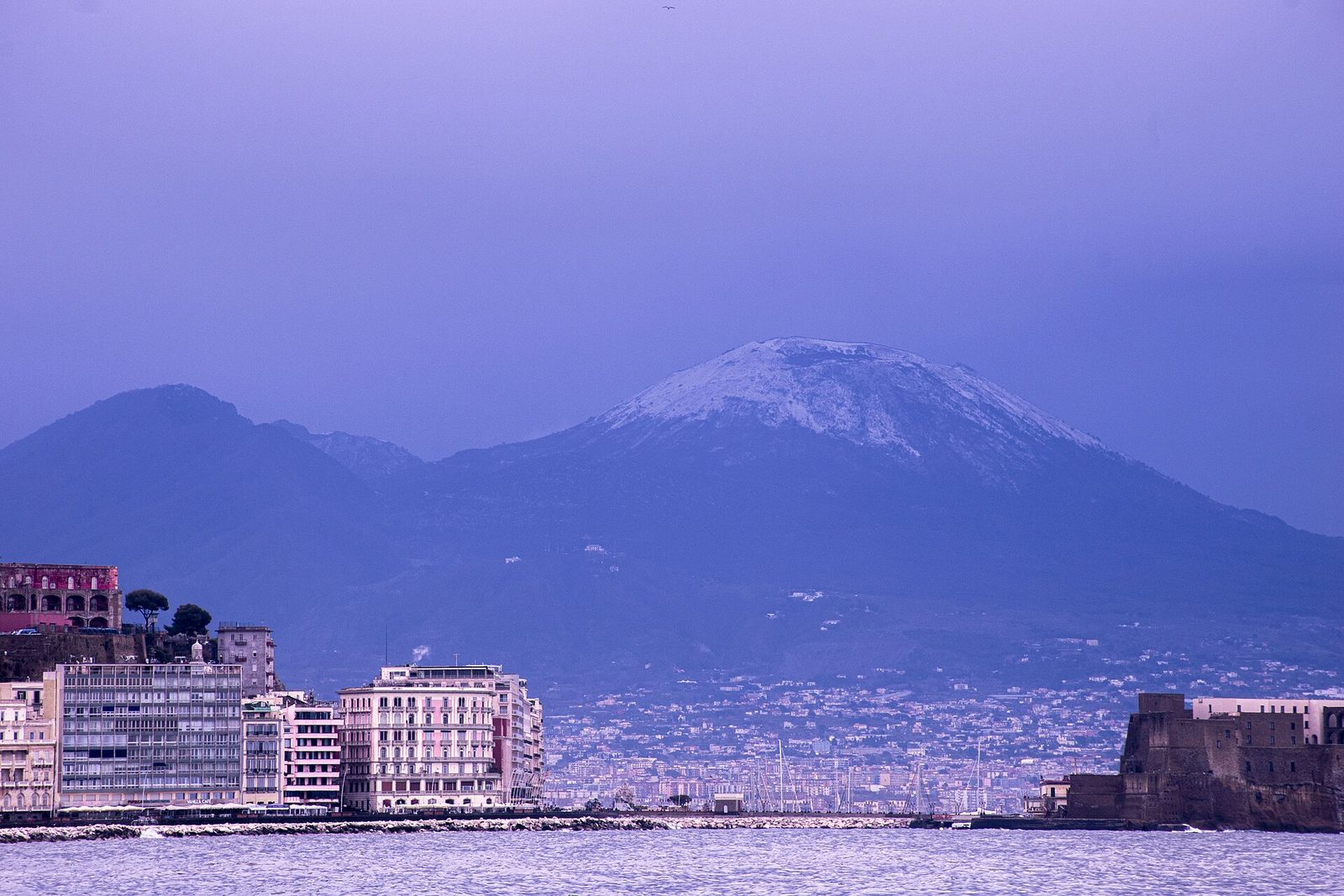 Snow on the summit of Mount Vesuvius above the Naples seafront on a clear winter day