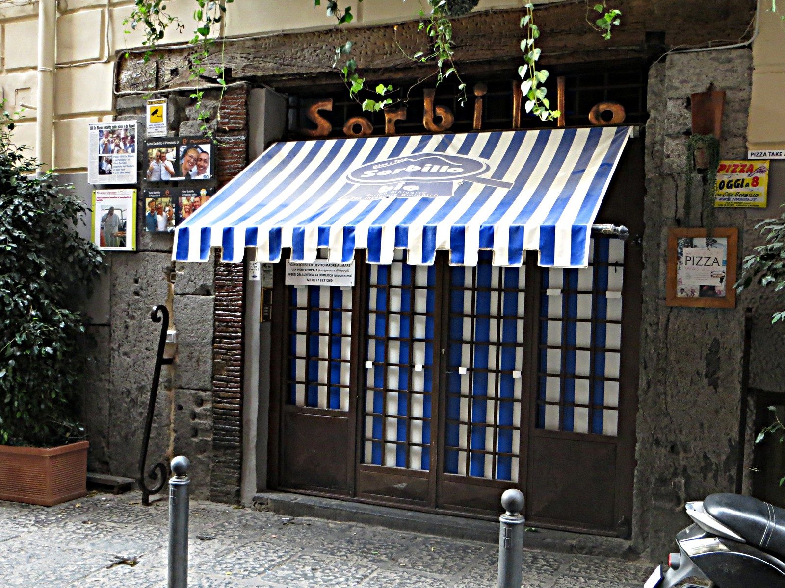 The blue-and-white awning of the Gino Sorbillo pizzeria on Via dei Tribunali in Naples