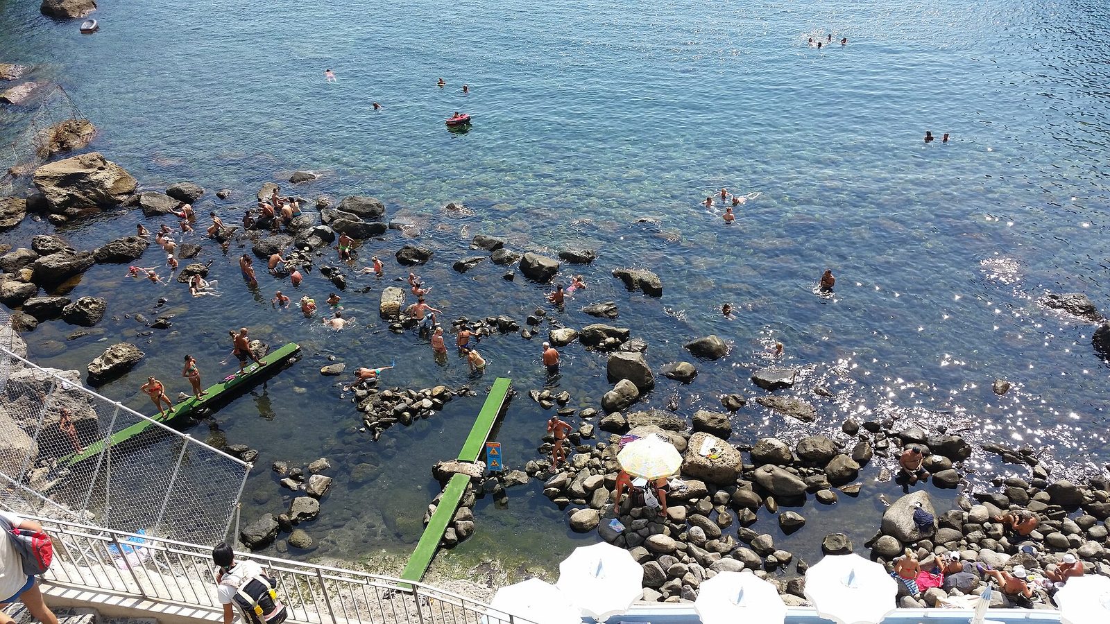 Bathers among the rocks and natural hot spring pools of the bay of Sorgeto on Ischia