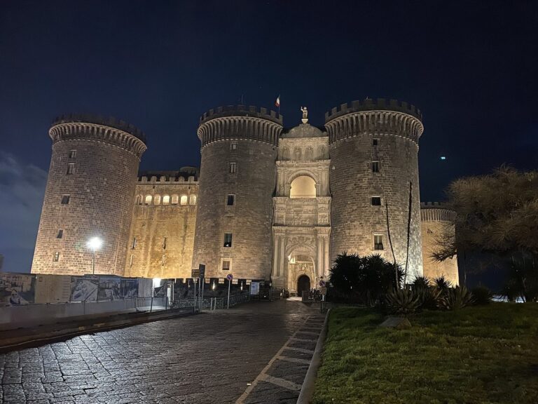 Castel Nuovo floodlit at night on Piazza Municipio in Naples, Italy