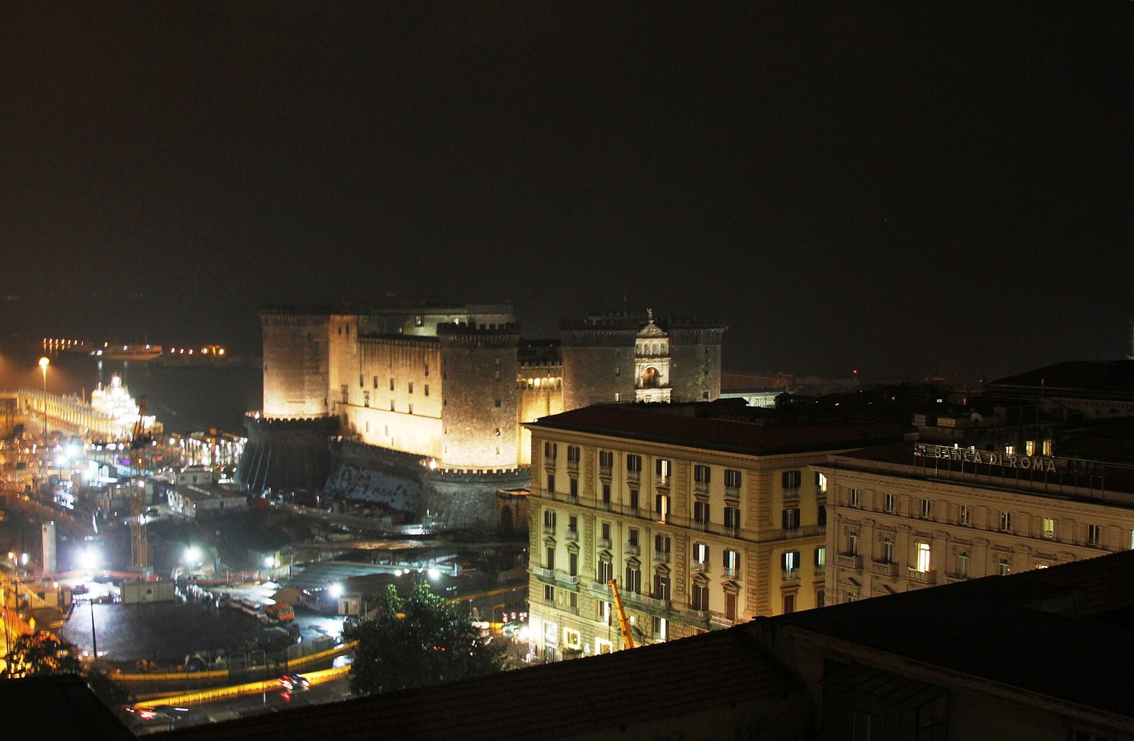 Castel Nuovo lit up at night seen from a hotel rooftop, a classic view of Naples nightlife