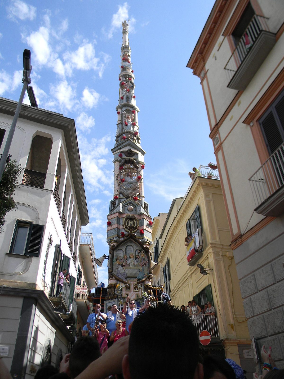A towering giglio carried through the streets of Nola toward Piazza Duomo during the Festa dei Gigli