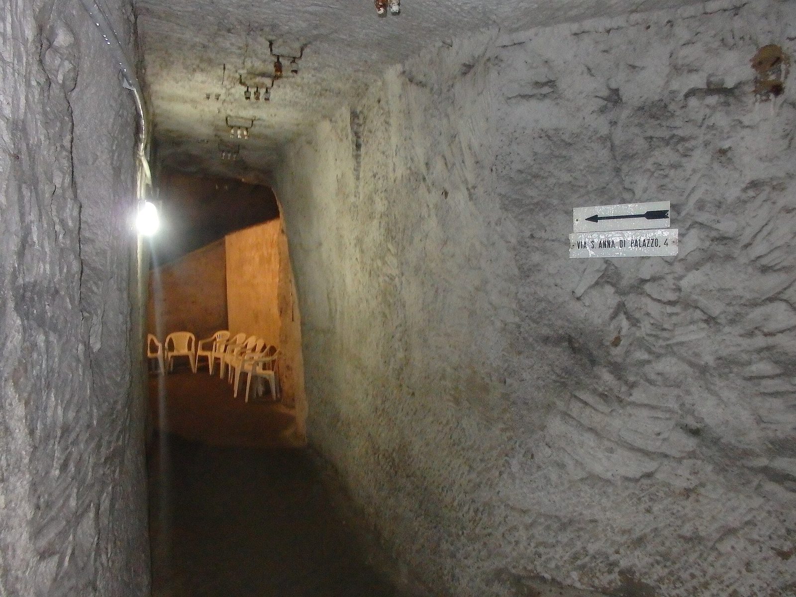 A narrow tunnel cut into yellow tuff in Napoli Sotterranea, the underground city beneath Naples