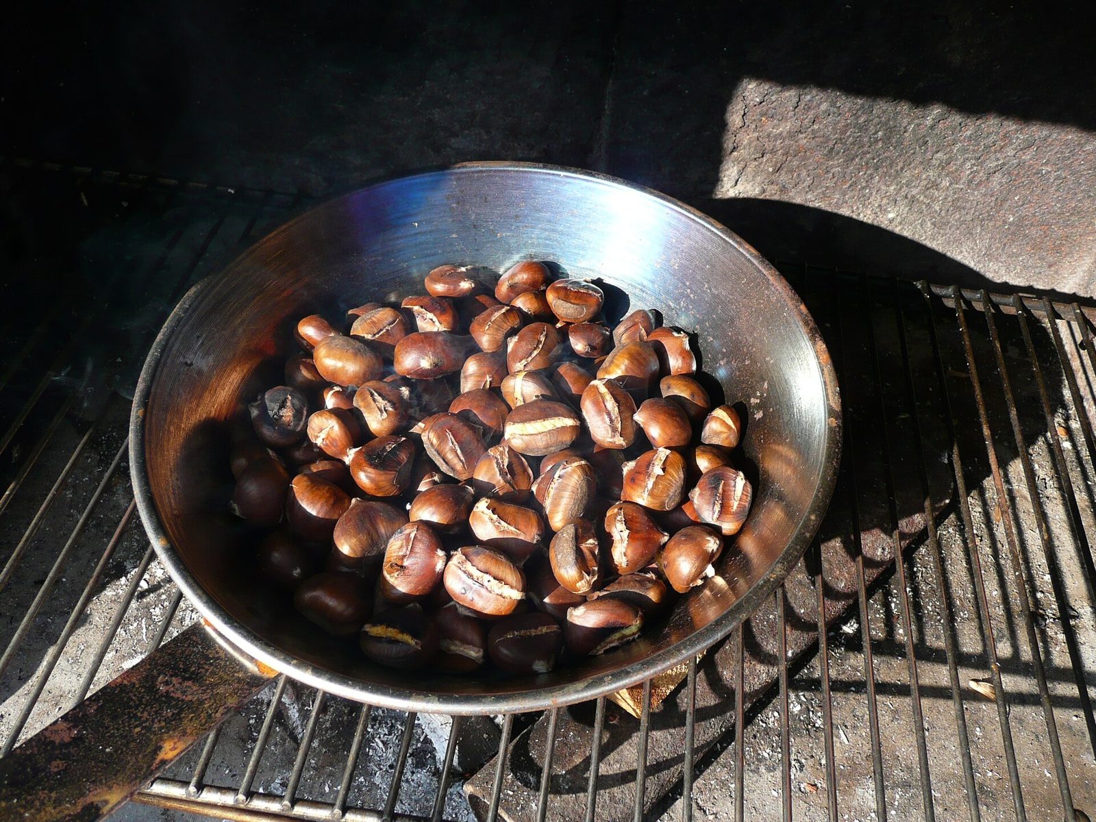 Chestnuts roasting in a perforated pan over a grill, a classic sight of Naples in November