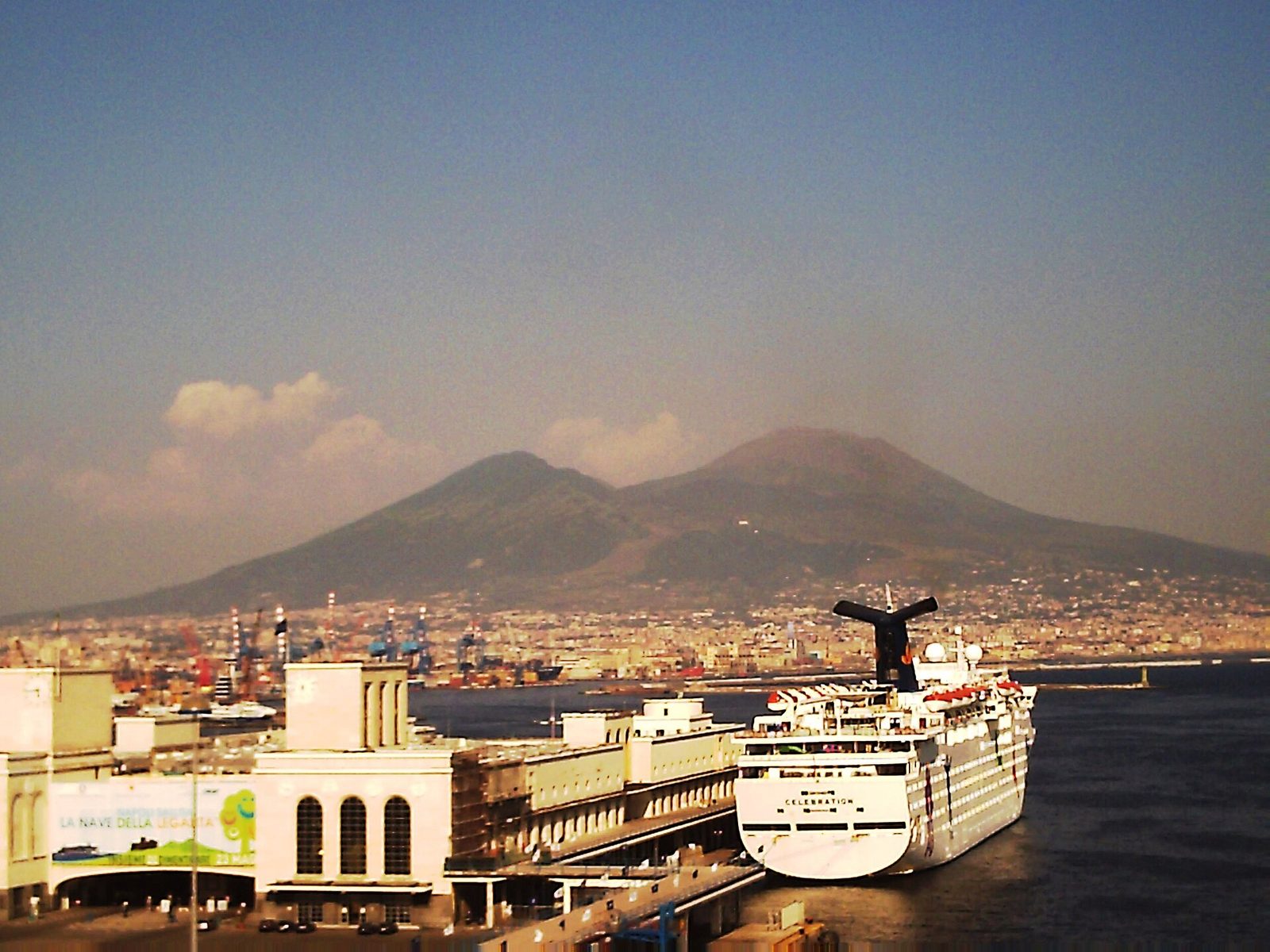 A cruise ship berthed beside the Stazione Marittima, the Naples cruise port, with Vesuvius behind