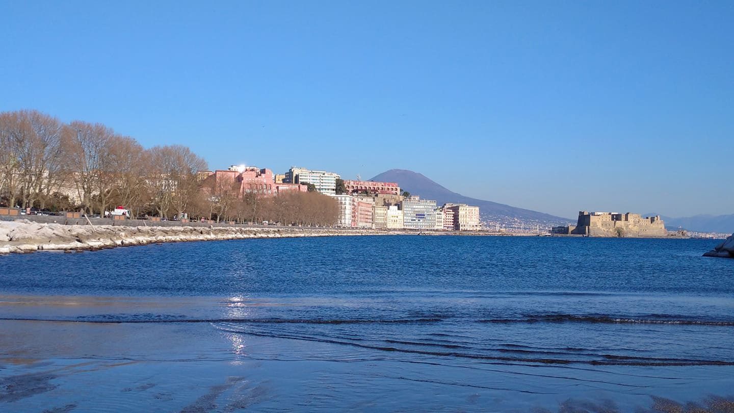 The Naples seafront with bare trees, Castel dell'Ovo and Vesuvius under a clear blue sky